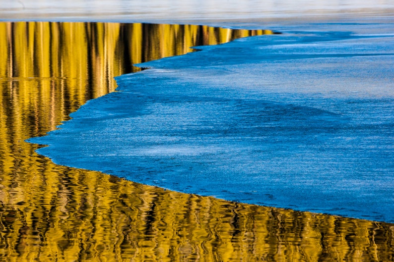 Surface Ice, Spring Thaw. A thin layer of ice on a glassy mountain lake.
